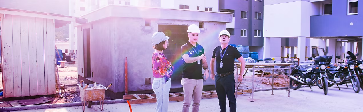 Equipe de engenheiros da Intertele em campo, com capacete e uniforme, em obra de condomínio